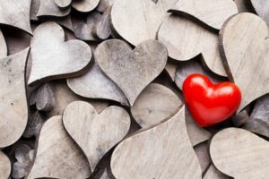 A Single Red Love Heart on Pile of Plain Wooden Hearts – What Does Love Mean - Sandra Harewood Counselling