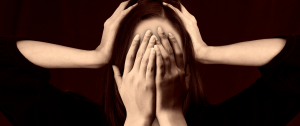 Stressed Woman With Her Hands Covering Her Face - What Your Physical Symptoms Can Teach You About Hidden Stress