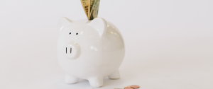 White piggy bank with money being deposited - Counselling and Coaching Rates - Sandra Harewood