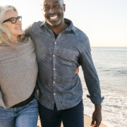 Couple mixed race couples walking hand in hand on the beach, symbolising connection and harmony in their relationship.