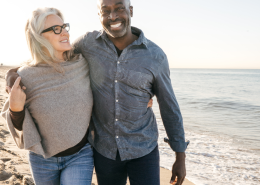 Couple mixed race couples walking hand in hand on the beach, symbolising connection and harmony in their relationship.