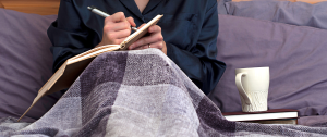 Woman journaling in bed - Sandra Harewood