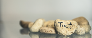 A pile of stones with the word trust painted on one - Healing from Infidelity - Sandra Harewood