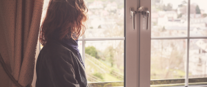 Woman siting alone looking through a window - Why Midlife Marriages Face Crisis—and How to Navigate Them with Compassion - Sandra Harewood