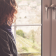 Woman siting alone looking through a window - Why Midlife Marriages Face Crisis—and How to Navigate Them with Compassion - Sandra Harewood