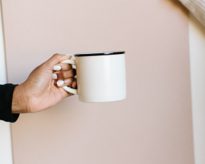A woman holding a mug, pausing thoughtfully as she decides between tea or coffee, symbolising mindful choice and inner discernment.