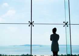 Woman looks of a window to the ocean - At a Relationship Crossroads? Why This Moment Deserves Care, Not Crisis