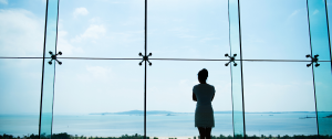 Woman looks of a window to the ocean - At a Relationship Crossroads? Why This Moment Deserves Care, Not Crisis