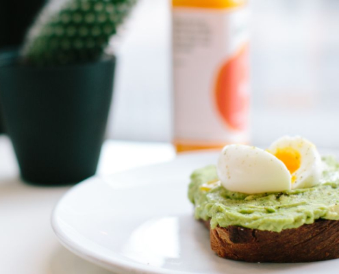 An alternative to pumpkin soup. Soft boiled egg and sliced avocado on toasted sourdough, served on a white plate. A simple, nourishing lunch that symbolises balance and self-care.