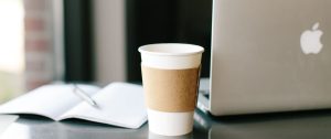 Laptop, coffee cup, and open journal on a table — representing practical self-reflection and growth to help save a marriage.