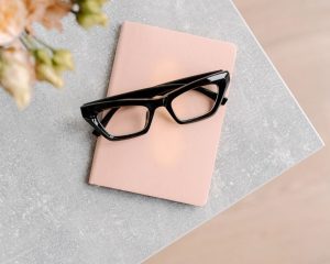 A pair of glasses resting on a pink diary, symbolising reflection, vulnerability, and honest self-expression in relationships.
