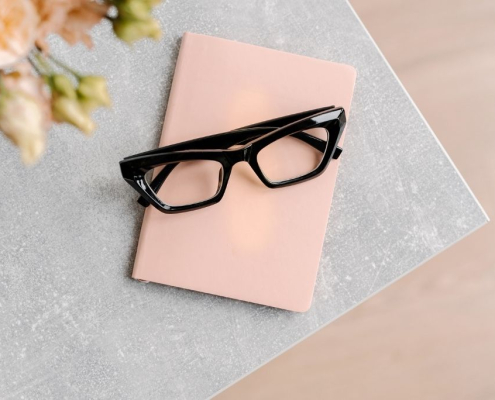 A pair of glasses resting on a pink diary, symbolising reflection, vulnerability, and honest self-expression in relationships.