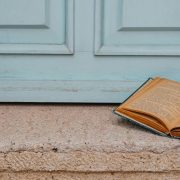 a an open book on Doorstep Against Vintage Blue Door Open book on the step of an antique light blue door, symbolising reflection at a relationship crossroads