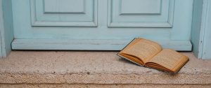 Open book on the step of an antique light blue door, symbolising reflection at a relationship crossroads