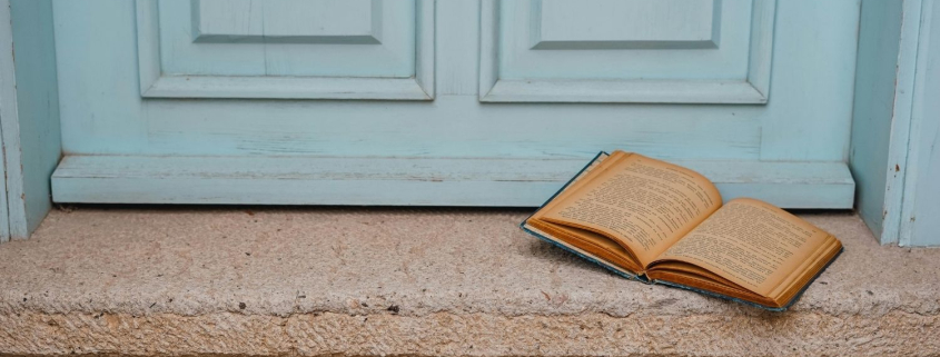 Open book on the step of an antique light blue door, symbolising reflection at a relationship crossroads