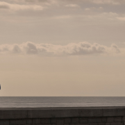 Couple standing apart looking out to sea, one partner wants to stay while the other feels unsure about the relationship