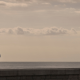 Couple standing apart looking out to sea, one partner wants to stay while the other feels unsure about the relationship