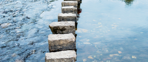 Stepping stones crossing calm water, symbolising the gradual process of making relationship decisions with clarity and confidence.