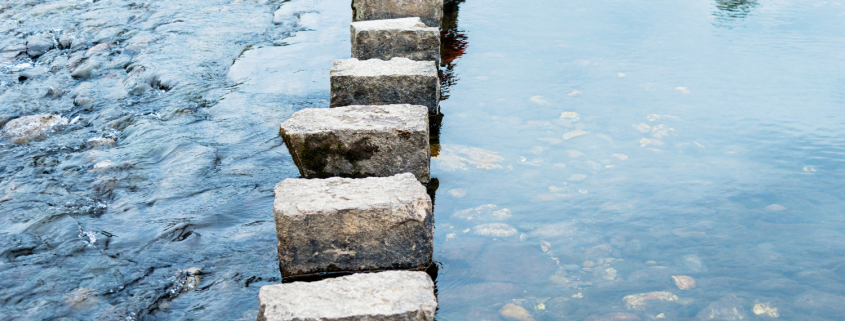 Stepping stones crossing calm water, symbolising the gradual process of making relationship decisions with clarity and confidence.