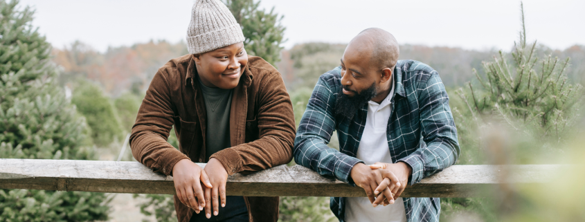 Two men leaning on a fence having a conversation.
